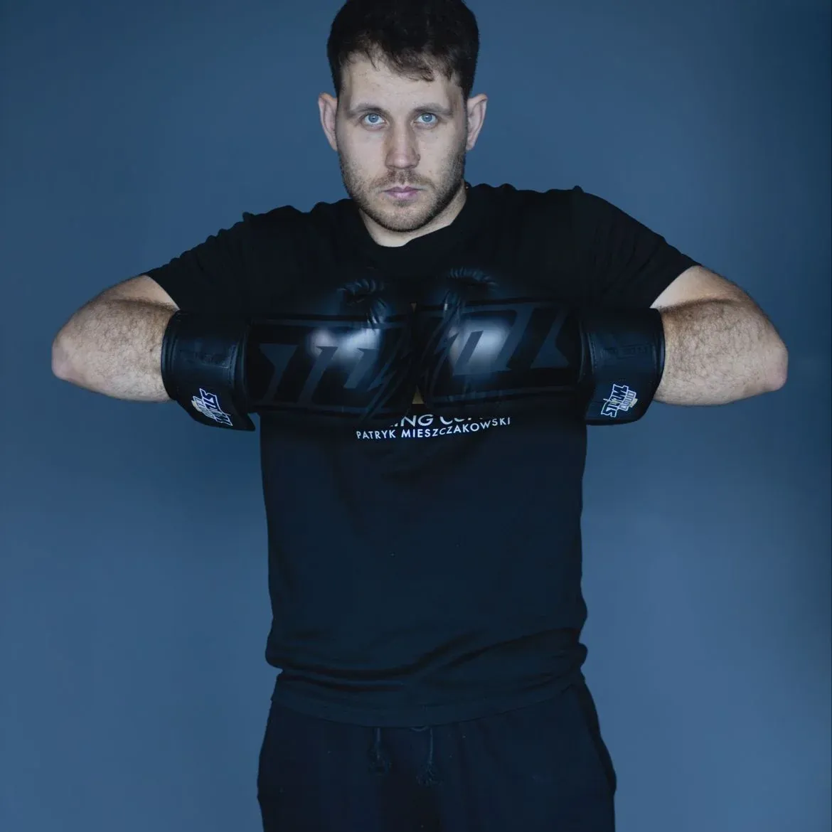 Patryk Mieszczakowski, trener PM Boxing Studio, w czarnych rękawicach bokserskich